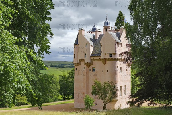 Pink castle surrounded by green countryside and trees, Craigievar Castle, Aberdeenshire, Scotland, United Kingdom