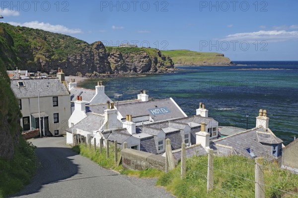 Village with hotel on coast with dramatic cliffs and blue water, Local Hero, Pennan, Aberdeenshire, Scotland, United Kingdom