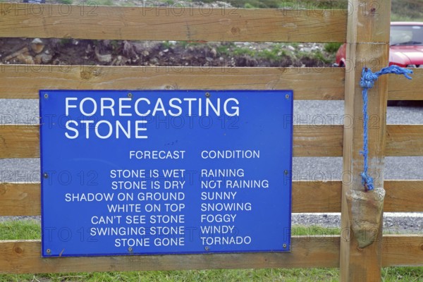 Wooden sign with blue board for humorous weather forecasting by predicting the state of the stone, Outer Hebrides, Hebrides, Scotland, Great Britain