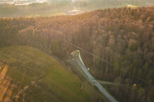 Aerial view of a wooded landscape with a winding road at sunset