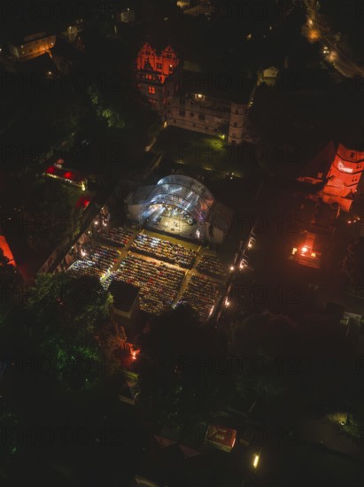 Aerial view of an open-air concert at night with illuminated spectators