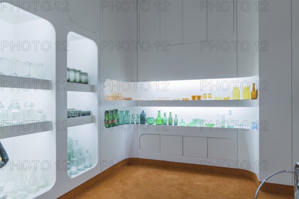 Interior with illuminated shelves full of glass bottles, modern white design