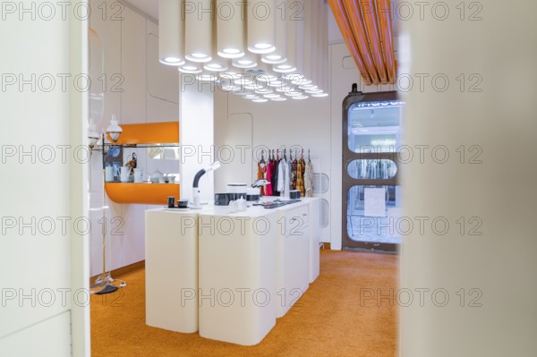Modern kitchen with orange carpet and unusual lighting, visible behind doors