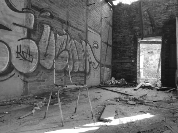 Abandoned room with graffiti and broken ceiling, empty chair ruin in the foreground, monochrome, Frankenwald nature park Park