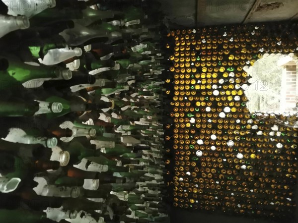 Artistic wall made of stacked glass bottles through which light shimmers, ruin house made of glass, Germany