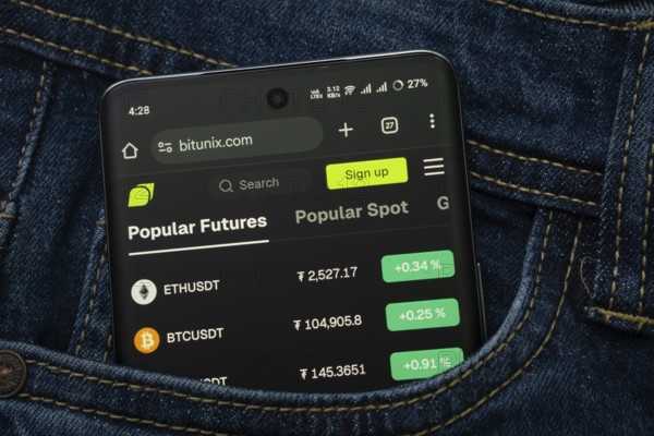 Dhaka, Bangladesh- 15 June 2025: A smartphone displaying the Bitunix.com web interface peeks out of a denim pocket