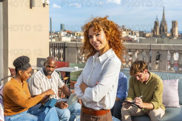 Team of diverse professionals working together on a city rooftop, engaging in discussions and tasks while experiencing a modern coworking environment and urban panoramic view
