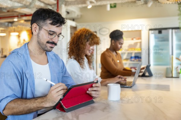 Diverse colleagues working on personal devices in a modern office, focusing on tasks and collaborating in a vibrant coworking space during a break or meeting