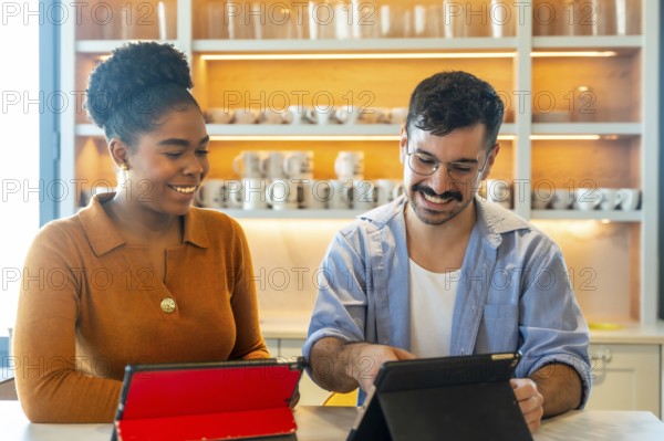 Diverse colleagues smiling and collaborating over tablets in a modern office pantry, sharing ideas and planning during a casual, productive break in a friendly workspace