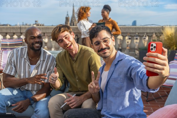 Diverse team of colleagues smiling and taking a rooftop selfie on a sunny urban terrace during a relaxed work break, enjoying casual conversation and city views