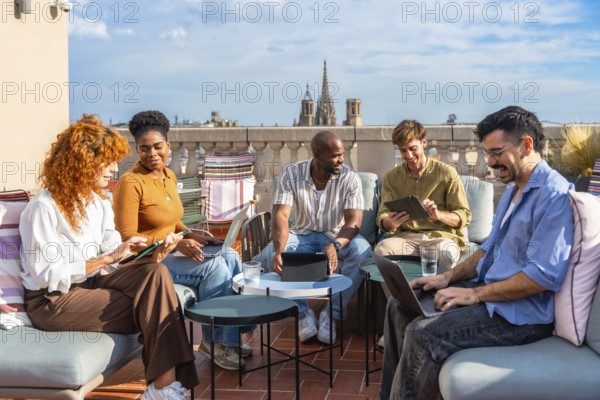 Diverse business colleagues working remotely from an outdoor rooftop office during a break, collaborating and communicating on a new startup project in the city
