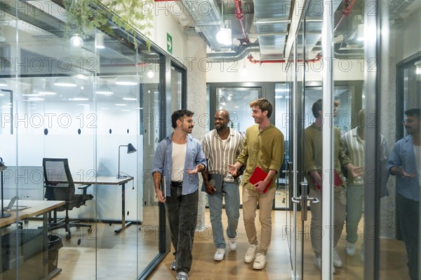 Diverse business colleagues walking and talking in a contemporary coworking office during a break, depicting teamwork, collaboration, and a strong professional relationship