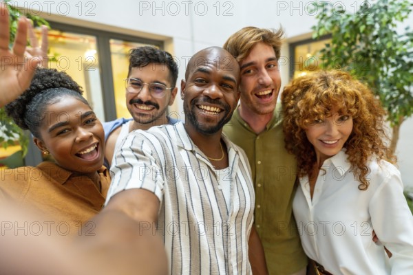 Group of happy diverse business colleagues smiling and looking at camera while taking a selfie during a relaxed office break, fostering teamwork and connection
