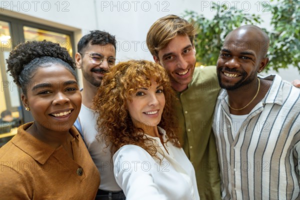 Diverse group of smiling business people looking at camera, capturing a self portrait together during a casual break from work in a bright, modern office or coworking space