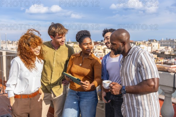 Diverse business people standing on a sunny urban rooftop, networking and collaborating while reviewing content on a digital tablet during a successful meeting