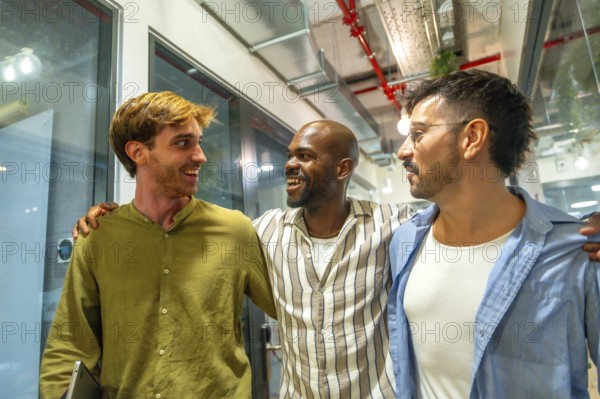 Diverse male colleagues walking together. Laughing and engaging in friendly conversation at a modern coworking office bringing together concepts of teamwork. Friendship. And professional collaboration