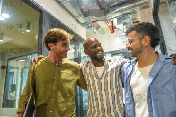 Smiling multiracial business professionals enjoying a moments of friendship and camaraderie, walking together inside a modern office during a work break