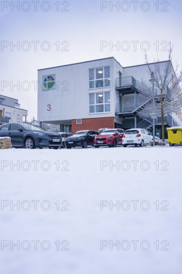 Modern buildings with snowy parking lot full of cars in winter, Gechingen, Calw district, Germany