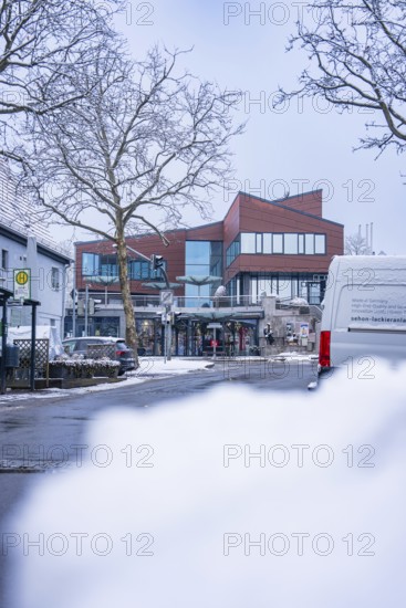 A modern street with snow-covered buildings and cars in winter, Town Hall, Gechingen, Calw district, Germany