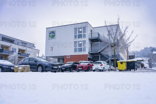 Snowy modern building with parked cars in the foreground in winter, Gechingen retirement home, Calw district, Germany