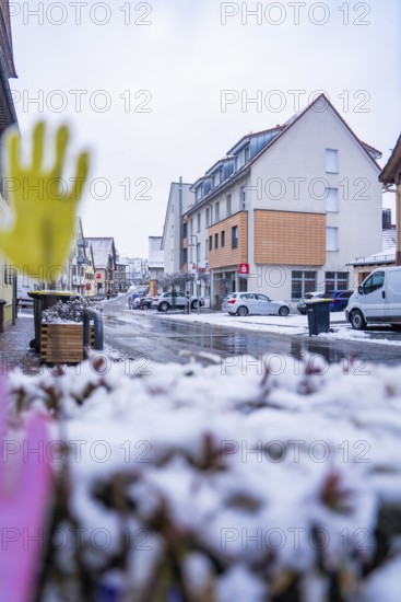 Snowy city street with residential buildings in the background and parked cars, Gechingen, Calw district, Germany