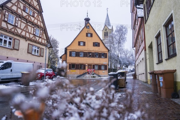 Snowy village road with traditional architecture and church in the background, Gechingen, Calw district, Germany