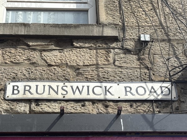 A road sign on a stone wall that says 'Brunswick Road. '