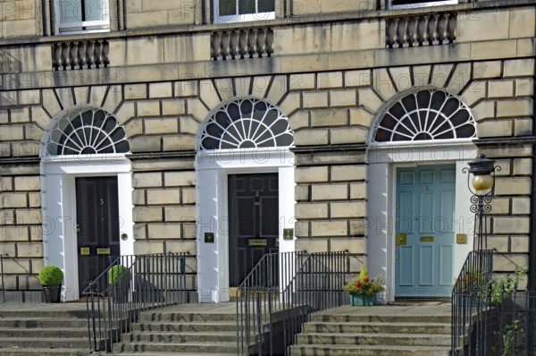 Three Georgian doors with symmetrical windows and stairs in front of them, Newtown, Edinburgh, Scotland, United Kingdom