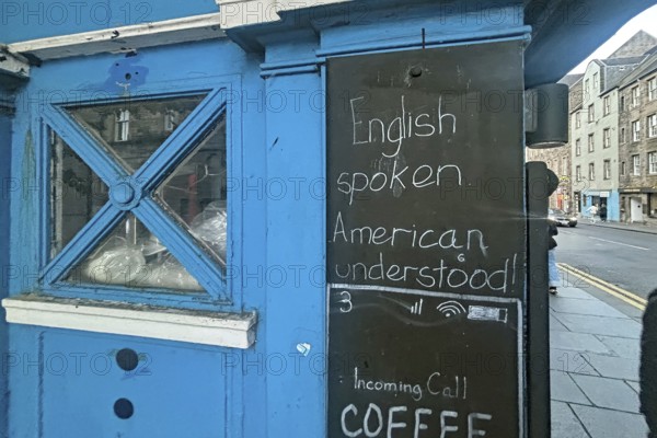 A blue-painted kiosk with a sign advertising English language skills, Humor, Royal Mile, Edinburgh, Scotland, United Kingdom