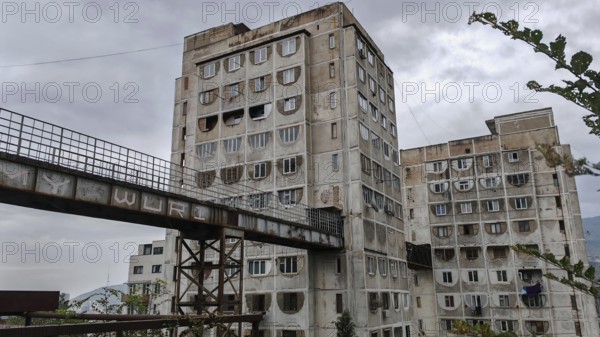 Three high-rise buildings connected by metal bridges under cloudy skies, nostalgic charm, architecturally interesting living silo, prefabricated buildings, Tbilisi, Georgia