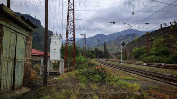 An abandoned railway line runs through a cloudy landscape surrounded by mountains, Armenia