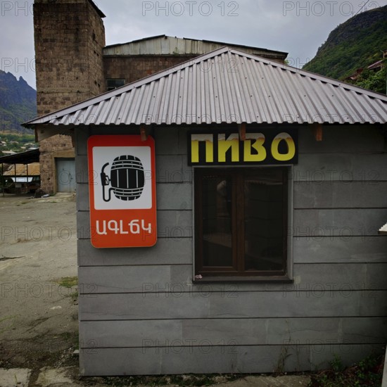 A small building with a beer shop sign, beer on tap, surrounded by an industrial background, Armenia