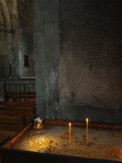 Candles burn in a dark stone church and create a peaceful atmosphere, Armenia