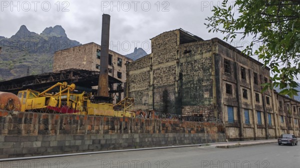 Abandoned industrial plant, factory with chimney and mountains in the background, Armenia