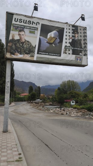 A large advertising poster on the side of the road, army looking for soldiers with mountains in the background, Armenia