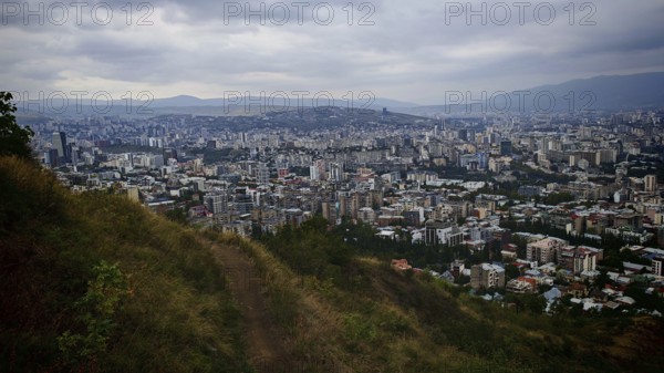 Hiking trail and view from a hill over a vast urban landscape, Tbilisi, Georgia