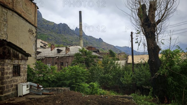 Old factory, ruins of buildings surrounded by mountains and dense vegetation, Armenia