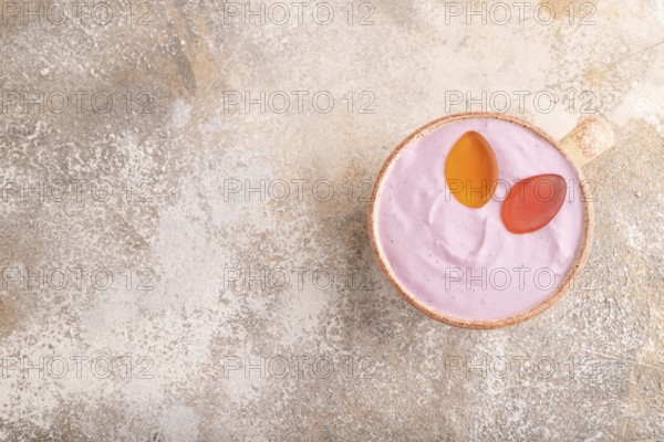 Purple Yogurt, with jelly candy on brown concrete background, top view, flat lay, copy space, minimalism
