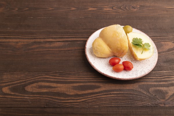 Smoked Mozzarella cheese, with tomatoes and olives on brown wooden background, side view, copy space