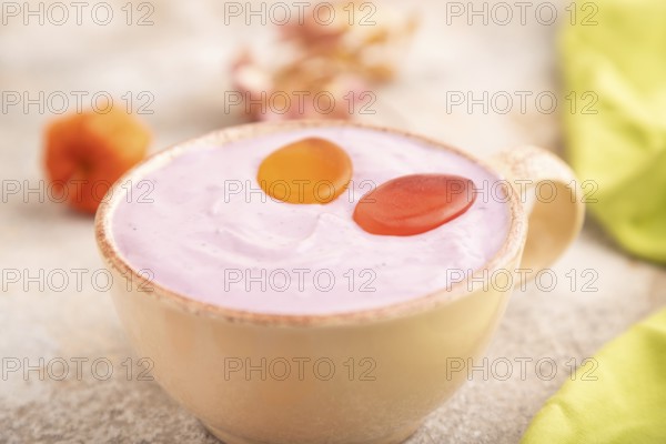 Purple Yogurt, with jelly candy on brown concrete background and green textile, side view, close up, selective focus, minimalism