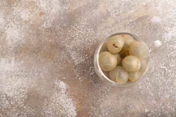 Ripe peeled Longan in glass on brown concrete background, top view, flat lay, copy space, minimalism