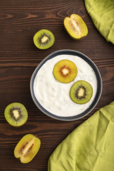Yogurt, with kiwi in blue bowl on brown wooden background and green linen textile, top view, flat lay, close up, minimalism