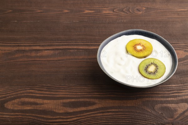 Yogurt, with kiwi in blue bowl on brown wooden background, side view, copy space, minimalism