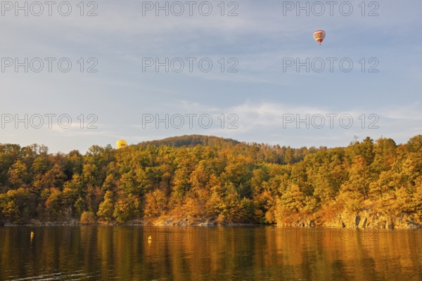 Hot air balloons over the Brno Reservoir (Brnenská prehrada) on the Svratka River on a sunny autumn day. The reservoir is located northwest of the city of Brno in the Czech Republic
