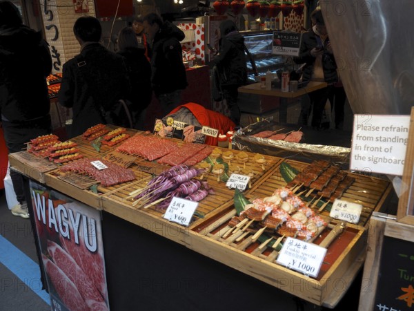 Lively market stand with various meats, including Wagyu, and other foods, Tsukiji Outer Market, Tokyo, Japan