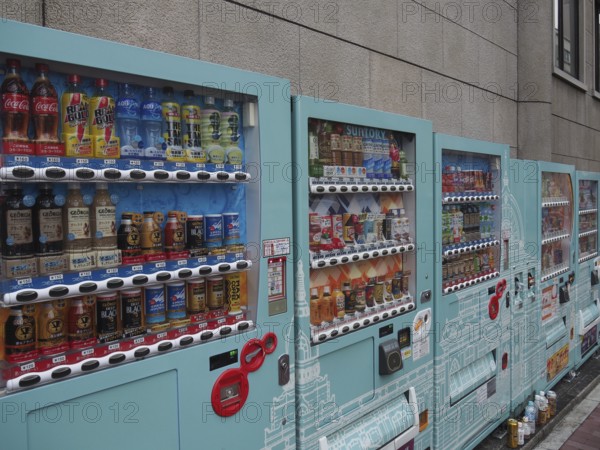 Row of colorful vending machines on a gray wall with a wide selection of drinks, Tokyo, Japan
