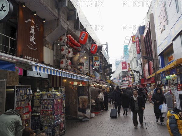 Bustling shopping street with shops and people decorated with red lanterns and signs, Ameyoko Market, Tokyo, Japan