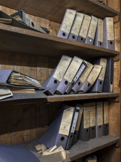 Shelves with dusty folders in the administration of a former GDR factory, Lost Place, Saxony-Anhalt, Germany