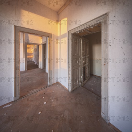 View through the open doors of an abandoned administration building in the light of the evening sun, Lost Place, Saxony-Anhalt, Germany