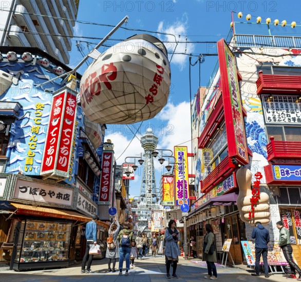 Lots of colorful signs in a pedestrian zone with shops and restaurants, behind Tsutenkaku Tower, Shinsekai, Osaka, Japan